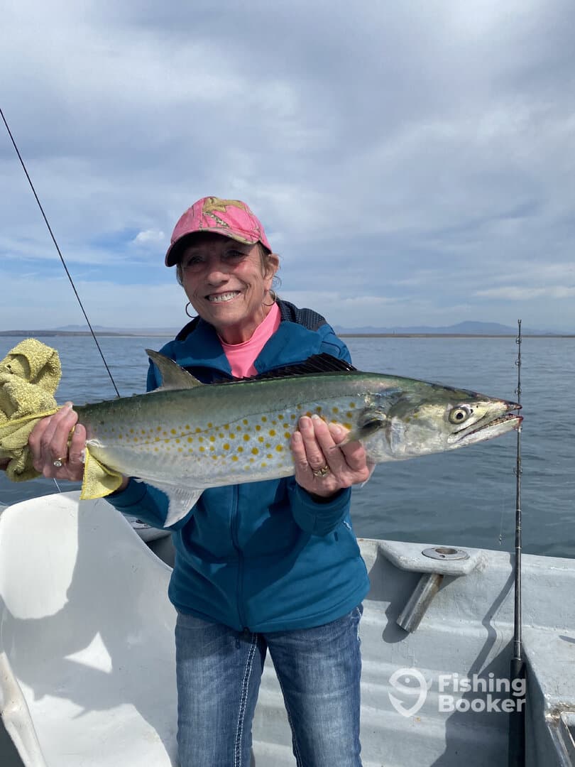 An angler proudly displaying a large Spotted Sea Trout while fishing on a boat, showcasing a successful day on the water.