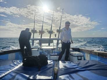 Two anglers aboard a fishing boat, enjoying a day on the water with fishing rods ready for action.