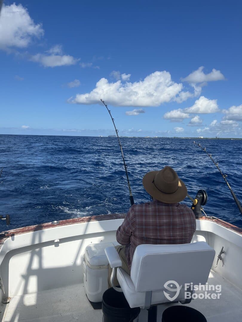 An angler actively reeling in a fish while fishing on a charter boat in open waters, showcasing a beautiful day at sea.