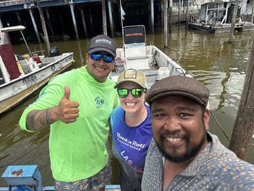 Three anglers posing together on a fishing boat at the dock, showcasing a vibrant atmosphere and camaraderie.