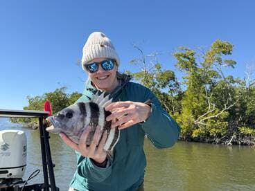 Angler proudly displaying a striped fish while fishing in a scenic coastal environment.
