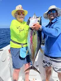 Two anglers proudly displaying a large Yellowfin Tuna while fishing offshore, showcasing a successful day on the water.