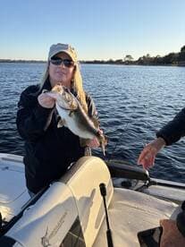 Angler proudly displaying a large Largemouth Bass while fishing on a serene lake.