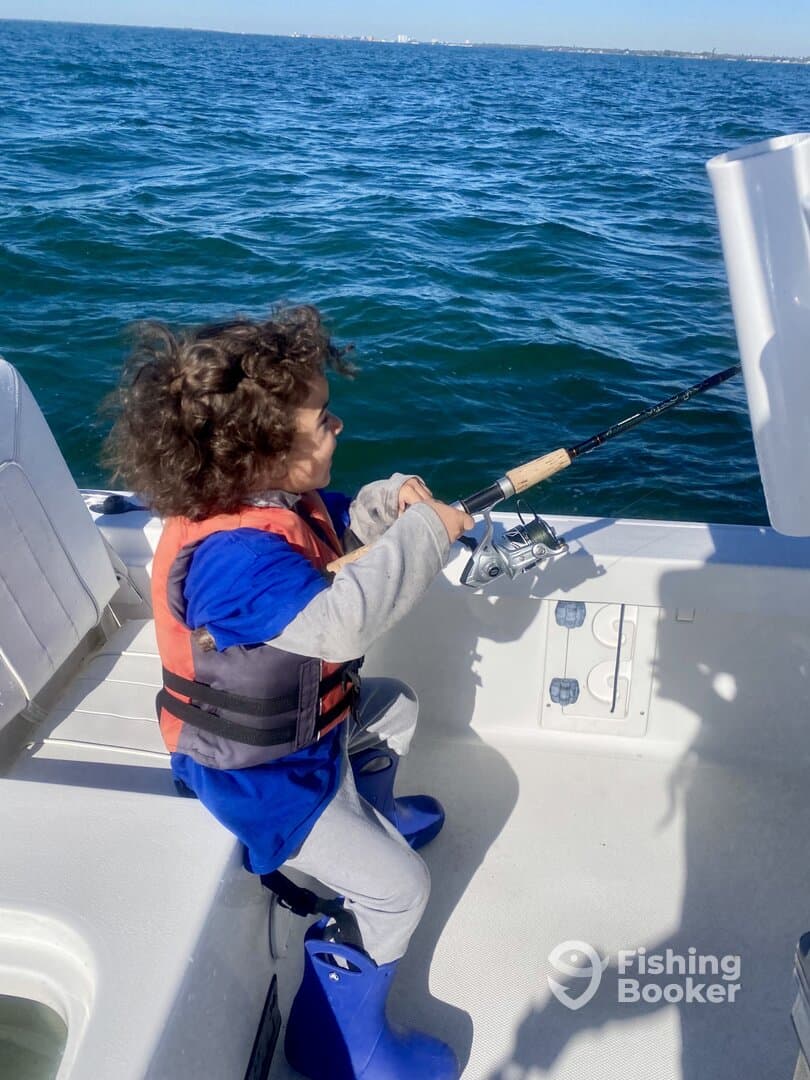 A young angler in a life jacket is actively fishing from a boat, showcasing the excitement of a day on the water.