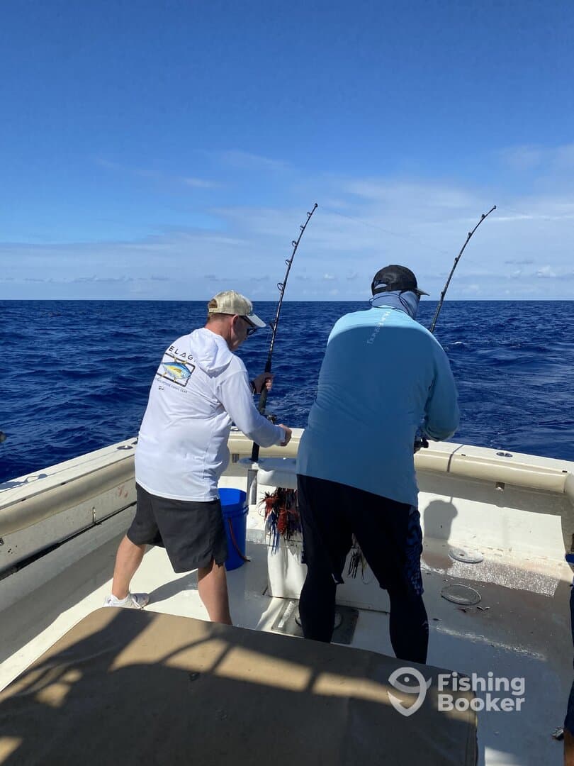 Two anglers engaged in reeling in their catch while fishing offshore, showcasing the excitement of deep-sea fishing.