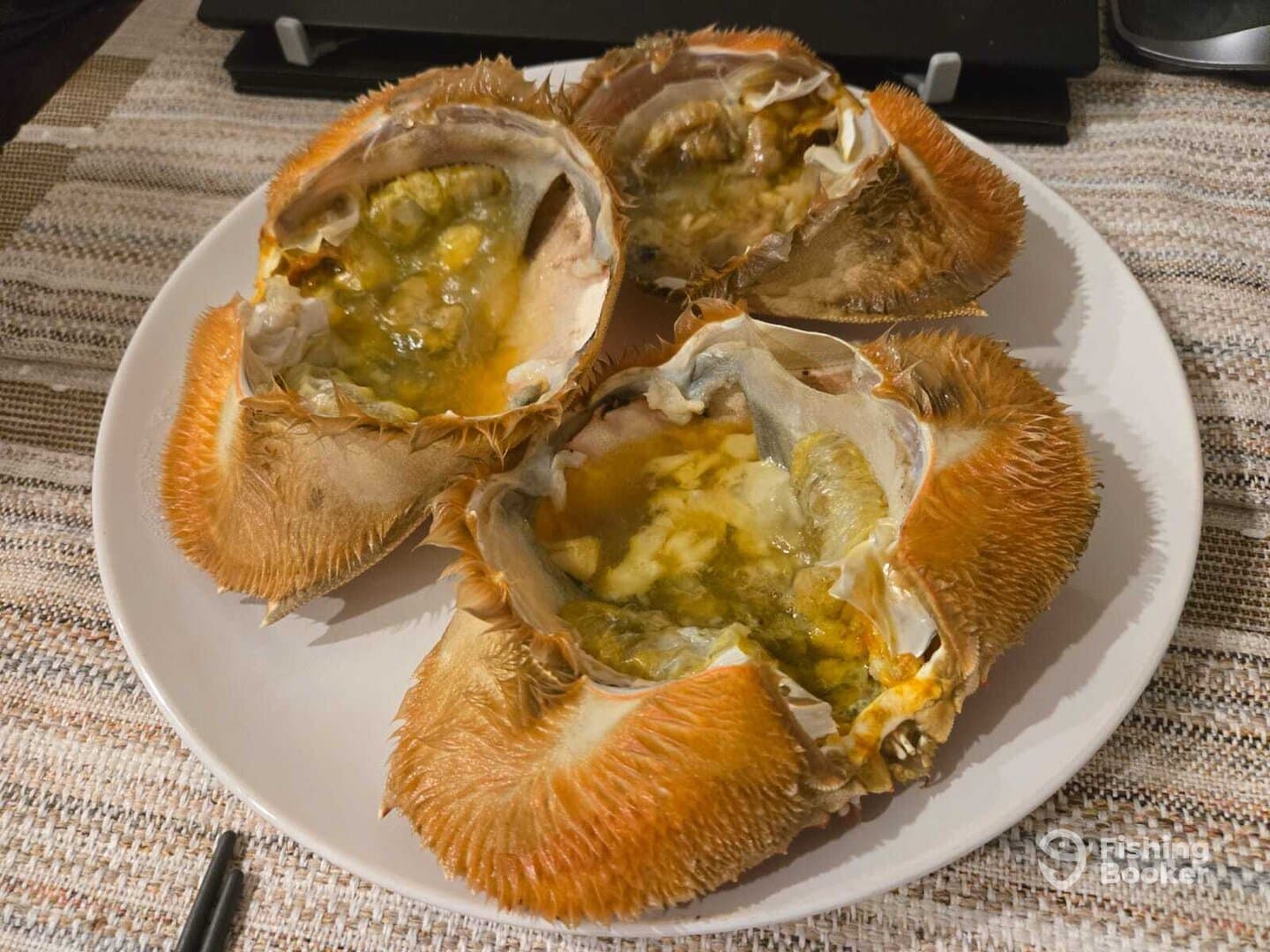 A close-up view of three crab shells on a plate, showcasing the interior, likely prepared for a seafood dish.