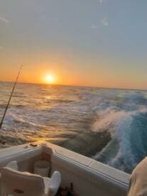 A scenic view from the boat during sunset, showcasing the tranquil ocean waves and fishing rod, perfect for a relaxing fishing trip.