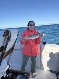 Angler proudly displaying a caught fish while aboard a boat in open waters.