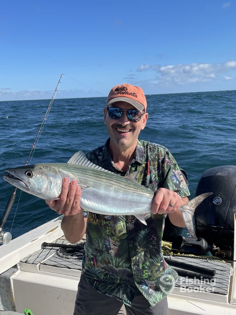 A smiling angler proudly displays a freshly caught fish while enjoying a day on the water.