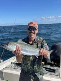 A smiling angler proudly displays a freshly caught fish while enjoying a day on the water.