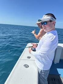 Two anglers actively fishing on a boat, enjoying a sunny day on the water.