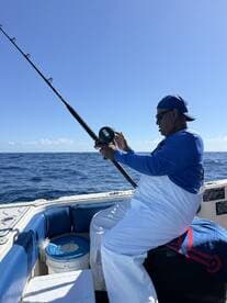An angler actively reeling in a catch while fishing on a boat in open waters, showcasing the excitement of the sport.