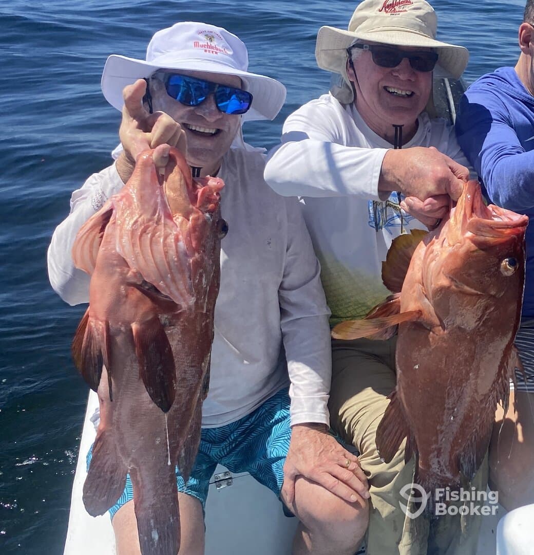 Two anglers proudly displaying their large Red Grouper catches while enjoying a day on the water.