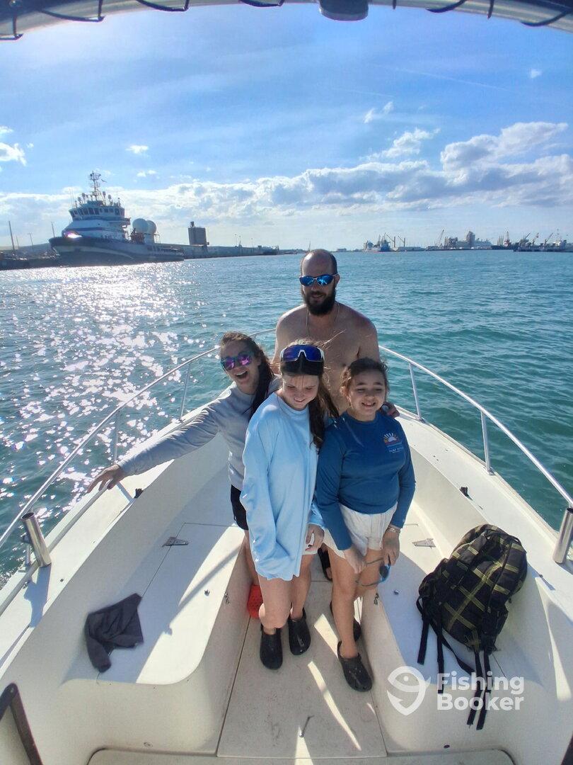 A family enjoying a day on the boat, with children and an adult posing together in a sunny fishing environment.