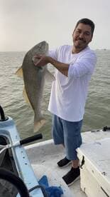 Angler proudly displaying a large Drum fish while fishing from a boat.