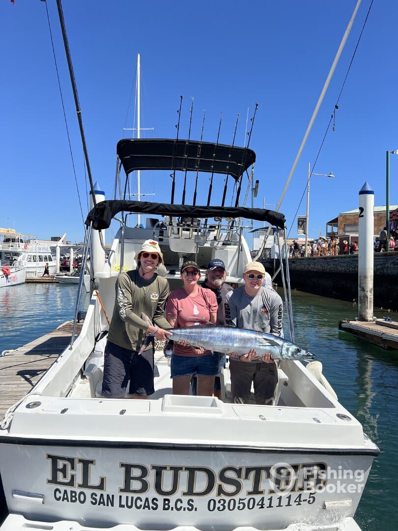 A family proudly displaying a large Wahoo on the boat 'El Budsto' after a successful fishing trip in Cabo San Lucas.