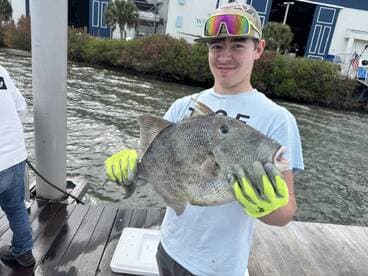 A young angler proudly displaying a large fish at the dock, showcasing a successful fishing trip.