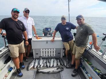 A group of four anglers proudly displaying their catch of multiple fish on a fishing charter, showcasing a successful day on the water.