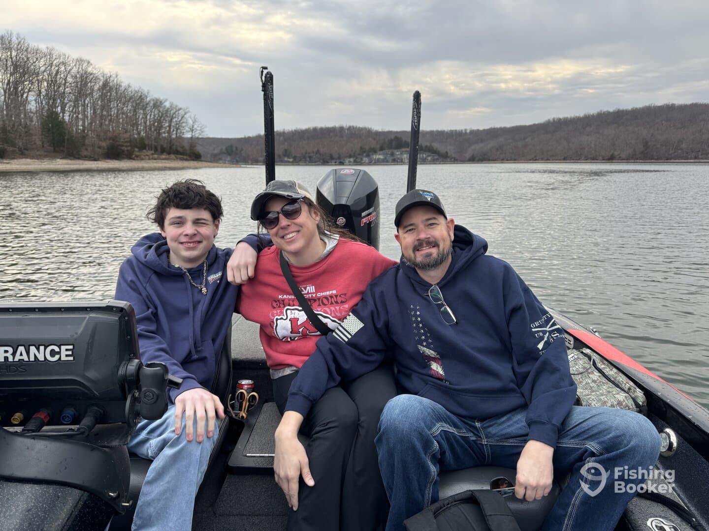 A family enjoying a day on the water in a fishing boat, with scenic views of the lake and surrounding trees.