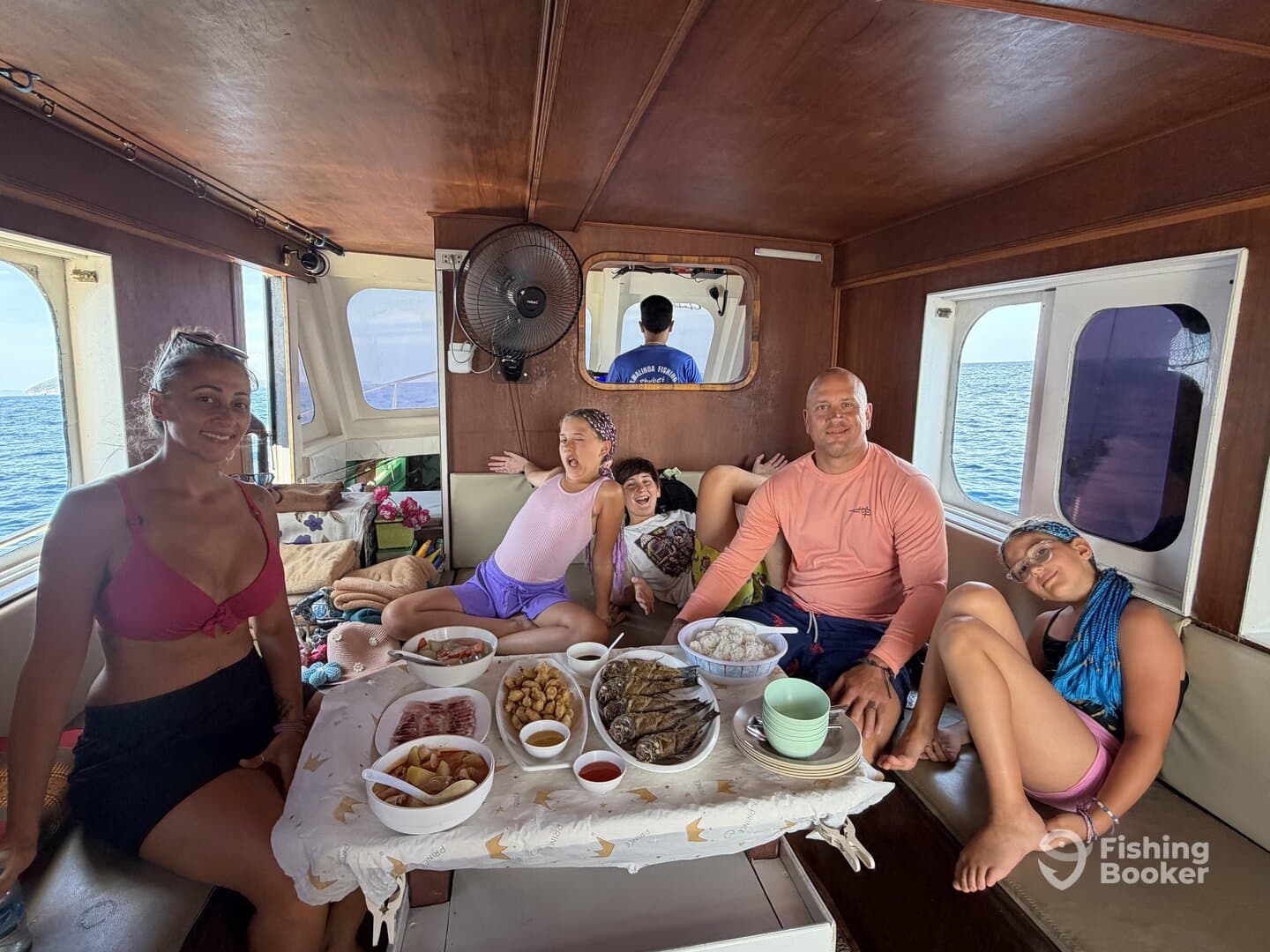 A family enjoying a meal inside the boat, showcasing a cozy interior with a view of the ocean.