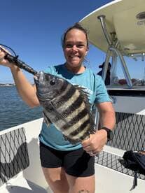 Angler proudly displaying a large Sheepshead caught while fishing on a boat, showcasing a beautiful day on the water.