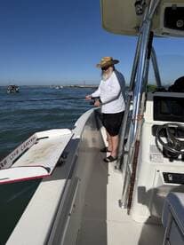 An angler casting a line from a boat, enjoying a day of fishing in clear waters with a scenic backdrop.