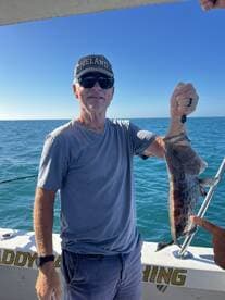 An angler proudly displaying a caught fish while enjoying a sunny day on the water.
