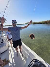 Angler reeling in a stingray while fishing in a calm waterway, showcasing an exciting moment on the boat.