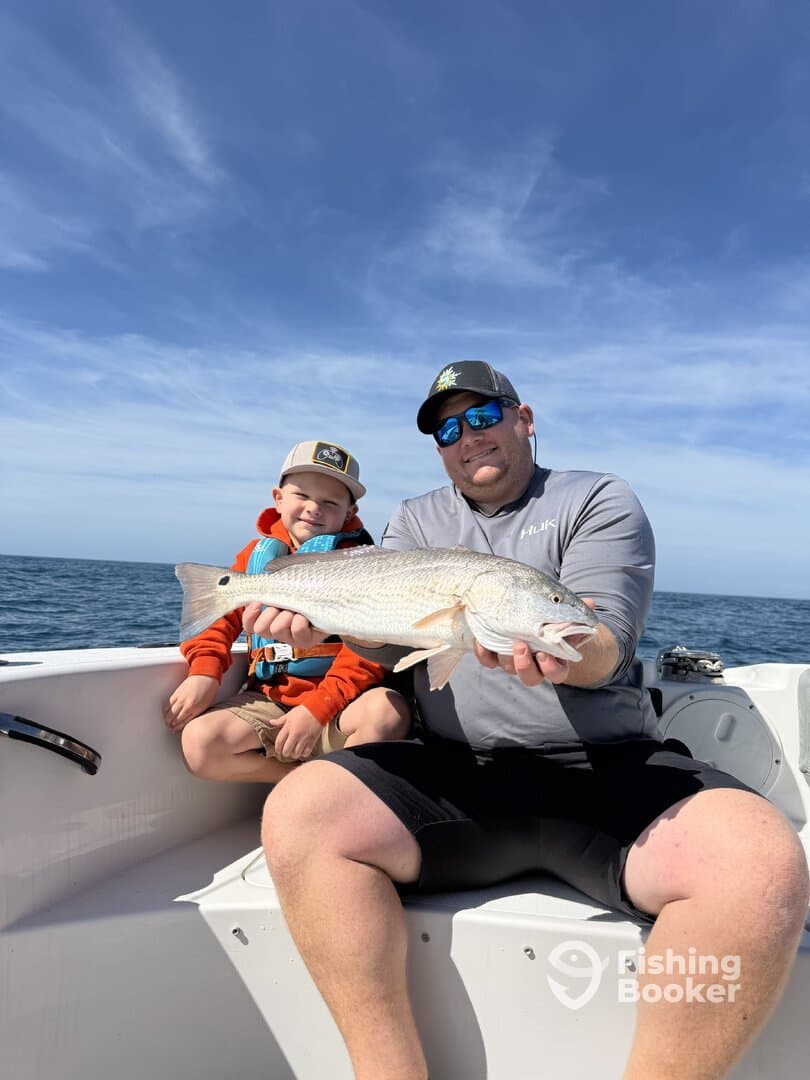 A proud father and son duo display a freshly caught Redfish while enjoying a day on the water.