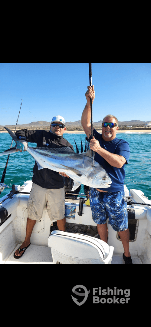 Two anglers proudly displaying a large fish on a boat, showcasing a successful day of fishing in clear waters.
