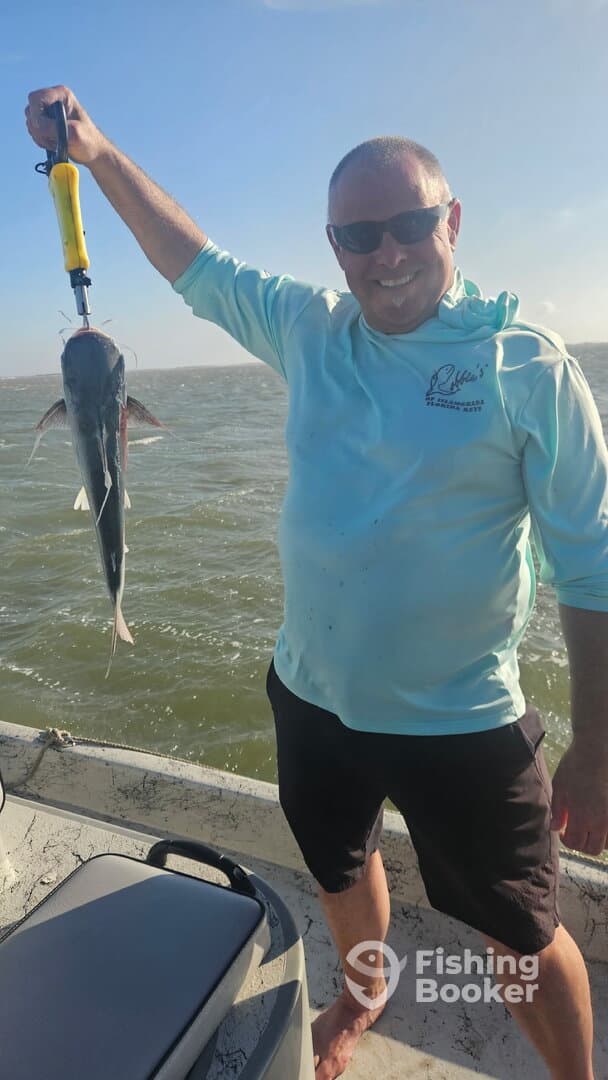 Angler proudly displaying a caught catfish while fishing on a sunny day.