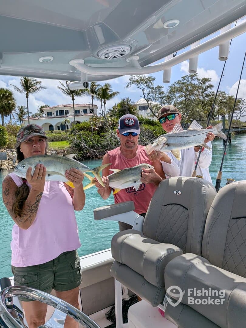 Three anglers proudly displaying their catch of Snook and other fish while enjoying a day on the water.