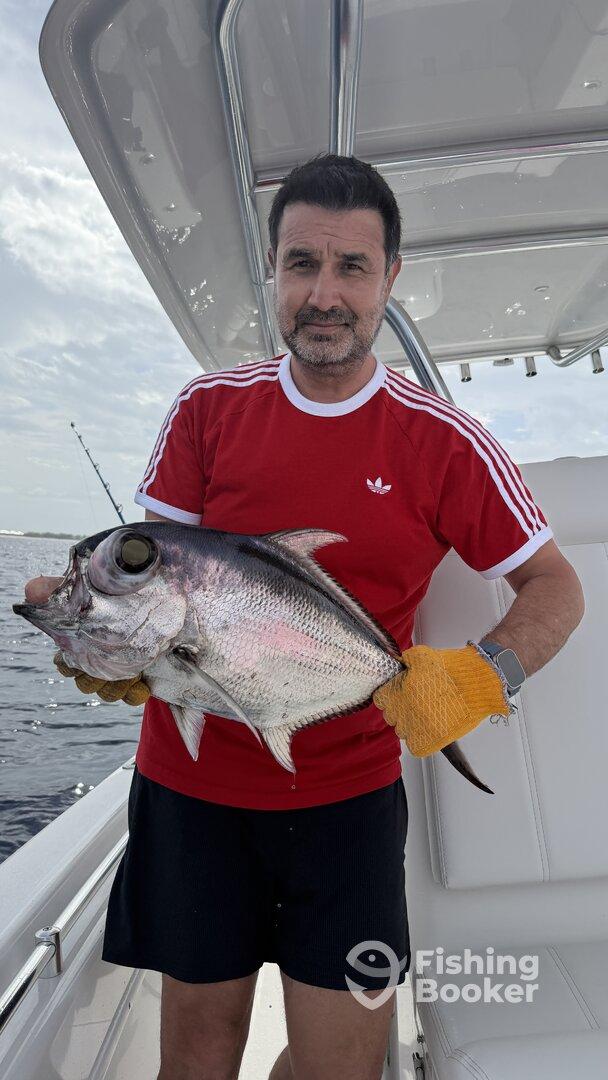Angler proudly displaying a large fish on a boat, showcasing a successful fishing trip.