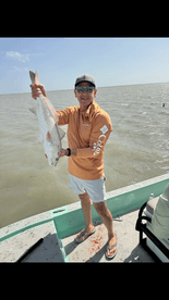 Angler proudly displaying a large Redfish while fishing on a boat in coastal waters.