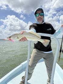 Angler proudly displaying a Speckled Trout while fishing on a sunny day, showcasing the excitement of a successful catch.