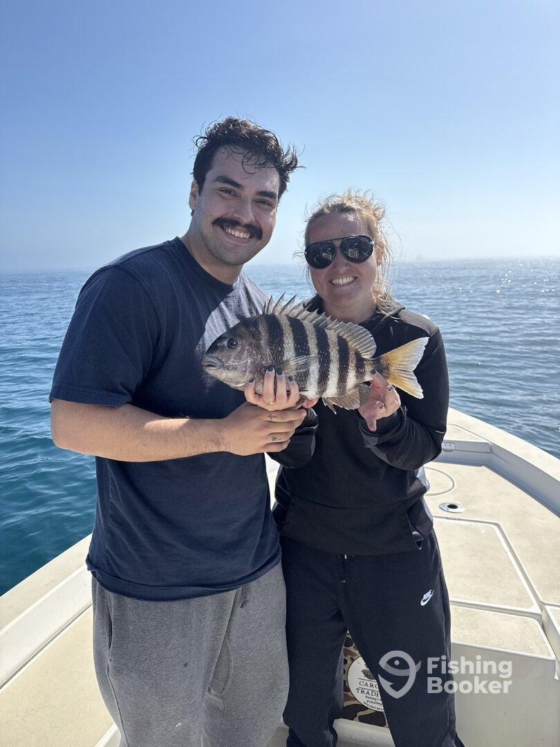 Two anglers proudly displaying a large Sheepshead fish while enjoying a sunny day on the water.