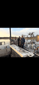 A group of anglers proudly posing with their catch of fish displayed on a board at the dock, showcasing a successful fishing trip.