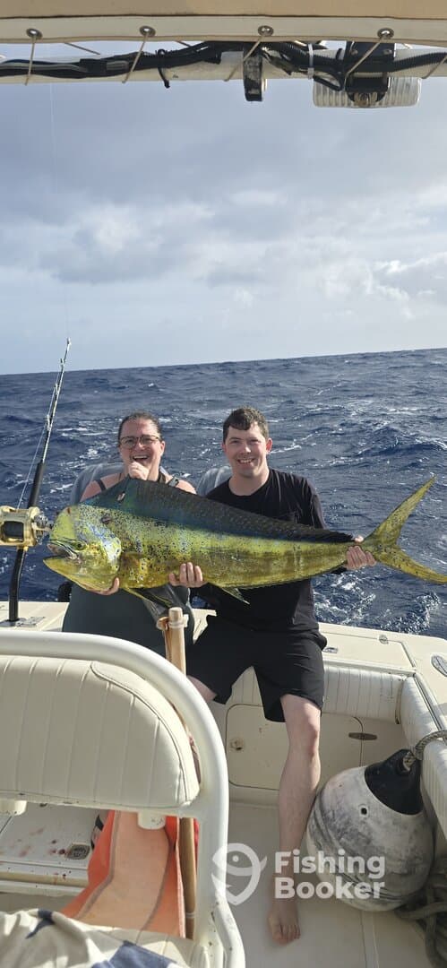 Two anglers proudly displaying a large Mahi Mahi while fishing offshore, showcasing a successful day on the water.