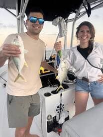 Two anglers proudly displaying their catches of Yellowtail Snapper while aboard a fishing boat.