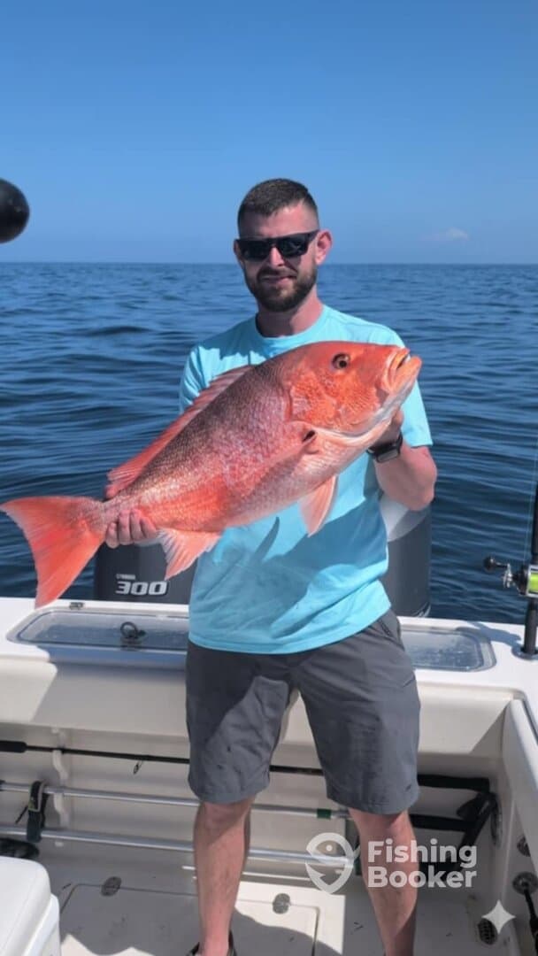 Angler proudly displaying a large Red Snapper while fishing offshore, showcasing a successful day on the water.