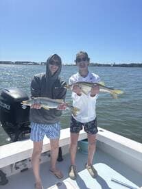 Two young anglers proudly displaying their catch of Snook while enjoying a sunny day on the water.
