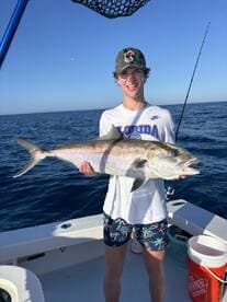 A young angler proudly displaying a large Amberjack while fishing offshore, showcasing the excitement of a successful day on the water.
