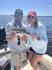Two anglers proudly displaying a large fish while enjoying a sunny day on the water.