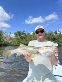 An angler proudly displaying a large Snook caught while fishing in a scenic coastal environment.