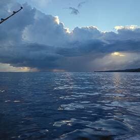 A serene view of the ocean under a dramatic sky, showcasing the calm waters and distant land.