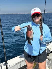 A young angler proudly displaying a colorful fish while fishing on a sunny day, showcasing the excitement of a successful catch.