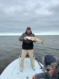 Angler proudly displaying a Snook caught while fishing from a boat in a coastal waterway.