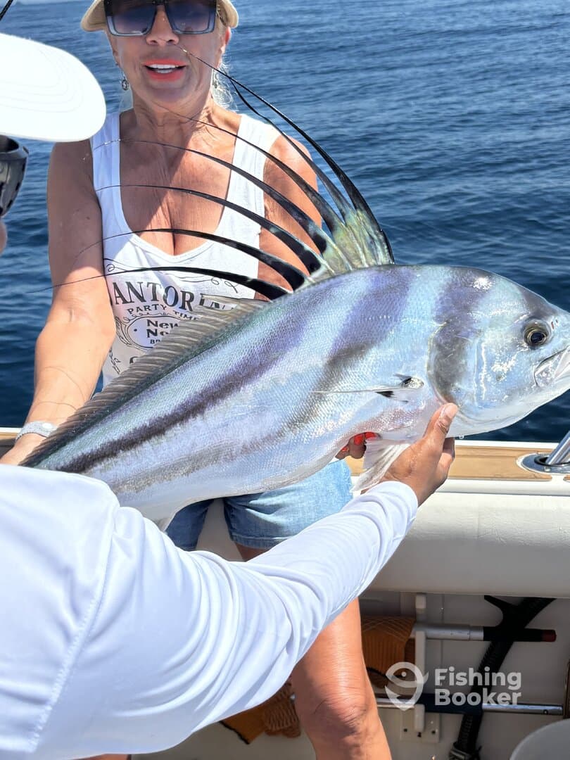A proud angler holding a large Roosterfish while enjoying a day out on the water.