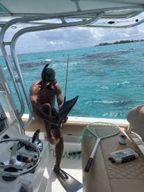 A snorkeler preparing to dive off a boat in clear turquoise waters, showcasing the boat's interior and equipment.