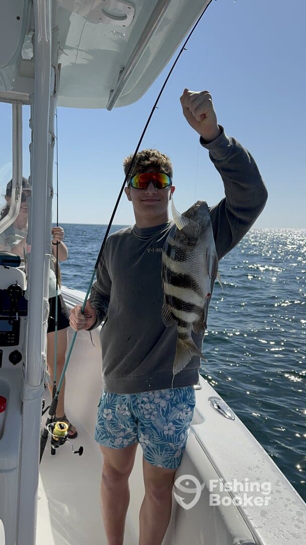 Young angler proudly displaying a striped fish while fishing on a sunny day.